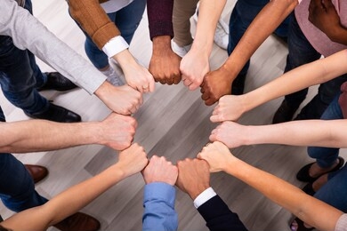 an overhead view of multi-ethnic people's hand joining their fist to form circle