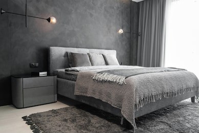 master bedroom for a lonely stylish man, a bachelor. modern room with trendy gray interiors, large king-size and stylish lamps.