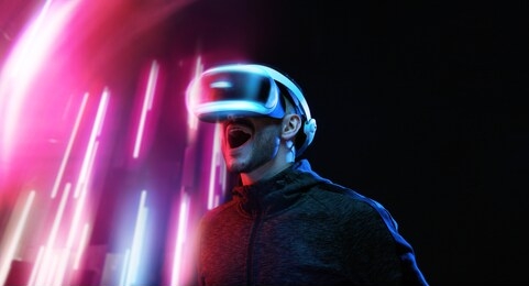 model young man with beard in glasses of virtual reality on dark background. augmented reality, science, future technology concept. vr. futuristic 3d glasses with virtual projection. neon light.