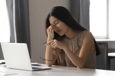 overworked stressed asian business woman employee holding glasses feeling pain in dry eye strain or headache suffer from bad blurry weak vision tired of computer work syndrome, sight problem concept