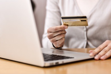 woman's hands holding a credit card and using computer keyboard for online shopping