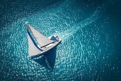 regatta sailing ship yachts with white sails at opened sea. aerial view of sailboat in windy condition.