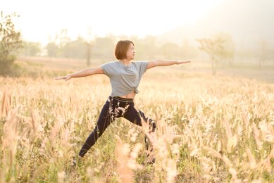 selective focus of young asian woman do yoga on a field during the moring under the golden sunligh.