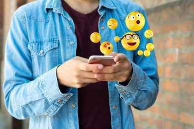 close-up of man using smartphone sending emojis. social concept.