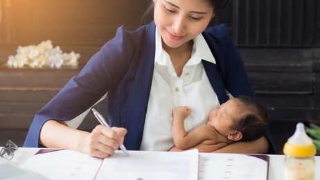 business woman holding baby in her arms while working, signing contract. single asian mum taking care of newborn in the office. can use for varieties of concepts. 