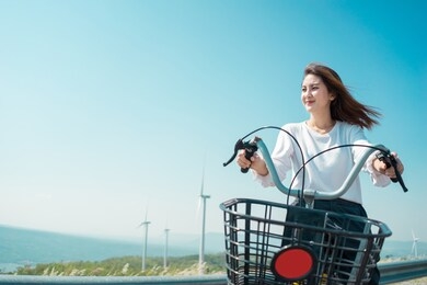 asian woman traveller smiling ride a bicycle for relaxing with natural on the mountain wind turbine field, green energy concept.
