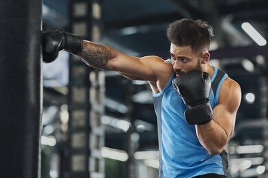 young sportsman boxing workout at gym, guy punching boxing bag, free space