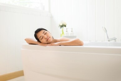 beautiful asian woman close eye and relax on bathtub in the morning,female lying body in water at hotel,copy space for text