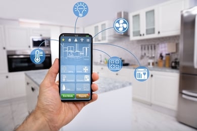 close-up of man's hand holding mobile with smart home control icon feature with kitchen background
