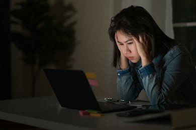 candid of young asian single female student work late night stress out with project research problem on computer laptop or notebook at home office. asian people occupational burnout syndrome concept.