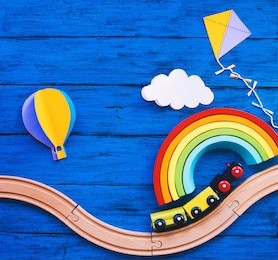 wooden toy train, railway for preschool child, wood rainbow, paper crafts on blue table. waldorf or montessori school background. kids dream, travel concept. educational toys for kindergarten children