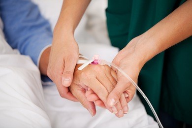 closeup of nurse holding patients hand in hospital
