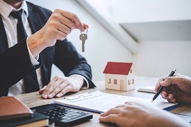 estate agent giving house keys to client after signing agreement contract real estate with approved mortgage application form, concerning mortgage loan offer for and house insurance.