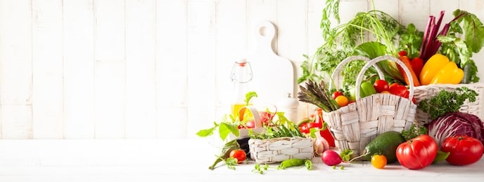 still life with various types of fresh vegetables in baskets on a white wooden table. concept of healthy eating, fresh vegetables.