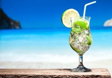 mojito cocktail with lime and mint on a beach background
