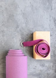 rolled yoga mat with cork  block and yoga belt. yoga practice props background. copy space.