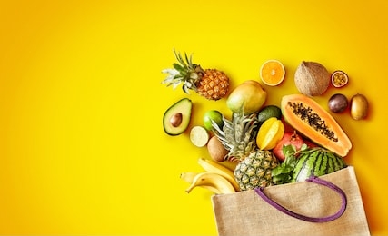 large variety of healthy fresh tropical fruit on exotic yellow background with copy space and vignette in panorama banner format