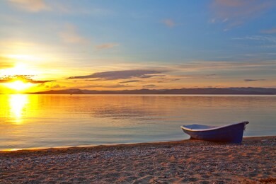 baikal lake in early summer morning. view of the rising sun from the shore of the small sea strait. fishing boat on a sandy beach. beautiful sunrise landscape. natural bright background