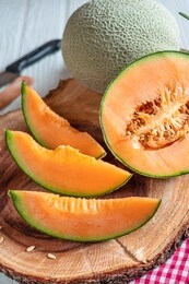 fresh of whole and sliced orange melon or cantaloupe on wooden cutting board and background wooden table. favorite fruit in summer concept.