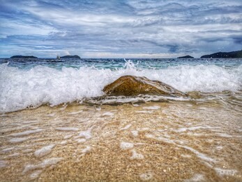 closeup with the sandy beach splashing water and swash wave in kota kinabalu, tanjung aru beach. sabah, malaysia.