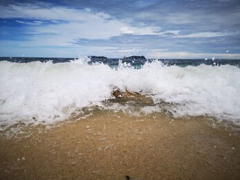 closeup with the sandy beach splashing water and swash wave in kota kinabalu, tanjung aru beach. sabah, malaysia.