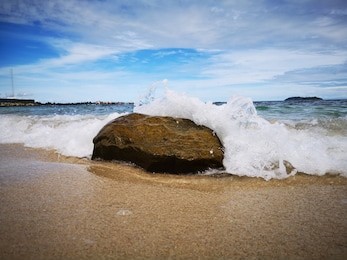 closeup with the sandy beach splashing water and swash wave in kota kinabalu, tanjung aru beach. sabah, malaysia.