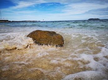 closeup with the sandy beach splashing water and swash wave in kota kinabalu, tanjung aru beach. sabah, malaysia.