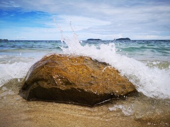 closeup with the sandy beach splashing water and swash wave in kota kinabalu, tanjung aru beach. sabah, malaysia.