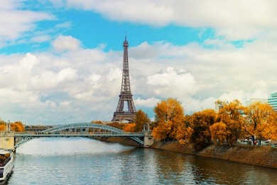 eiffel tour over seine river with yellow trees, paris, france at fall