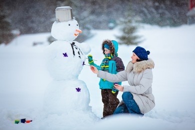 little boy with his mother painting a snowman
