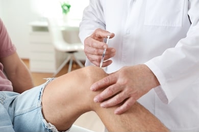 doctor giving patient injection in clinic, closeup. knee problem treatment
