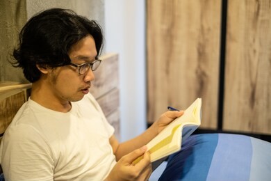 asian handsome man reading a book on the bed