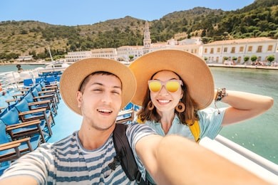 happy couple in love taking selfie on a deck of a sea cruise ship wearing hats. vacation and travel concept