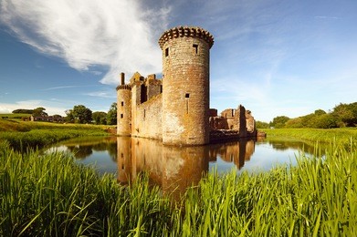 caerlaverock castle reflecting on the moat that surrounds the castle. dumfrieshire, scotland.
