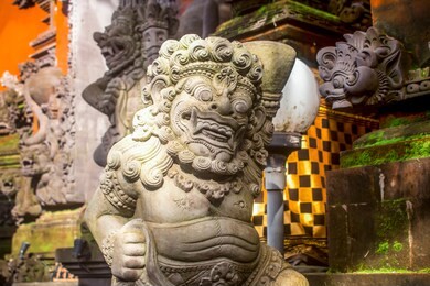 close up of gray stone sculpture of the bhoma creature at ubud palace in bali. carved in traditional balinese style.