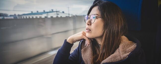 banner or web page of asian young lady passenger sitting in depressed mood beside the window inside train which travel between town when travel alone for escape the chaos,traveller and depress concept