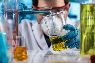chemical engineer mixing samples in the investigation laboratory / researcher holding test tube and beaker with fluids samples for analysis in chemical lab
