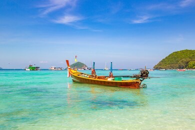 traditional long tail boat on coral (ko he) island near phuket island, thailand in a summer day