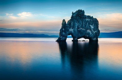 hvitserkur is a spectacular rock in the sea on the northern coast of iceland. legends say it is a petrified troll. on this photo hvitserkur reflects in the sea water after the midnight sunset.