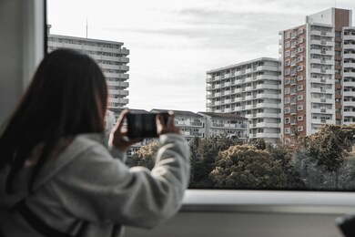 girls are taking pictures of the view by mobile phone at the window of the train.
blurred girl image in brown tones.