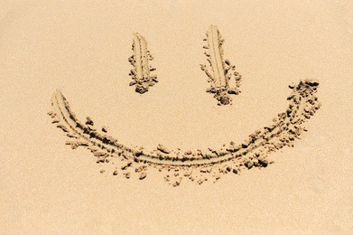 a smiley face drawing on a sand