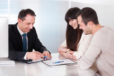 happy young couple discussing with consultant in office