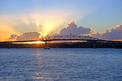 amazing sunset, flare though the clouds, auckland harbor bridge, new zealand