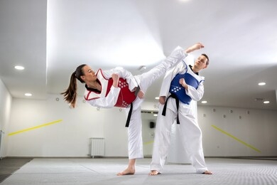 young woman training martial art of taekwondo with her coach, sportsmanship concept 