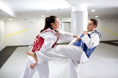 two taekwondists exchanging punches and kicks in training wearing protective gear, sports concept