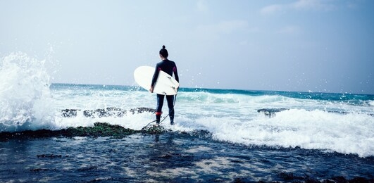 woman surfer with surfboard going to surf