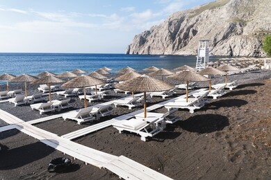 sunbeds and parasols on blank snd beach. kamari, santorini island, greece