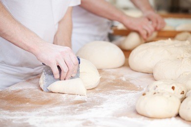 bakers making handmade loaves of bread in a family bakery shaping the dough into tradional shapes