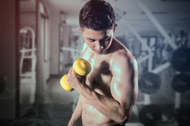 portrait of a muscled young man looks sweaty while lifting a dumbbell and exercising in the gym center