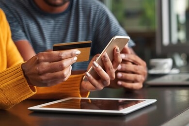 woman in café holding credit card and mobile phone